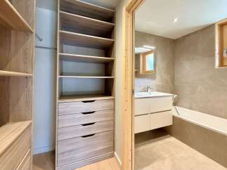 Discover this modern bathroom featuring a sleek vanity, a deep soaking tub, and elegant tiled walls.