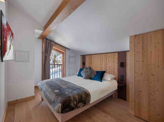 Experience cozy mountain living in this charming bedroom featuring a comfortable bed adorned with plush pillows and a stylish throw.