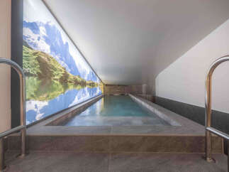 Immerse yourself in tranquility with this stunning indoor swimming pool, featuring a breathtaking panoramic mural of a serene mountain lake.