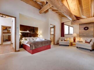 Experience rustic luxury in this charming bedroom featuring exposed wooden beams and a cozy, inviting atmosphere.