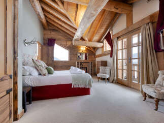 Experience rustic charm in this mountain chalet bedroom, featuring exposed wooden beams and a cozy fireplace.