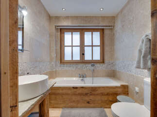 Experience rustic luxury in this charming bathroom, featuring a deep soaking tub set against a backdrop of natural stone tiles and warm wooden accents.