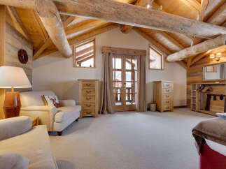 Experience rustic charm in this spacious attic bedroom, featuring exposed wooden beams and a cozy seating area.