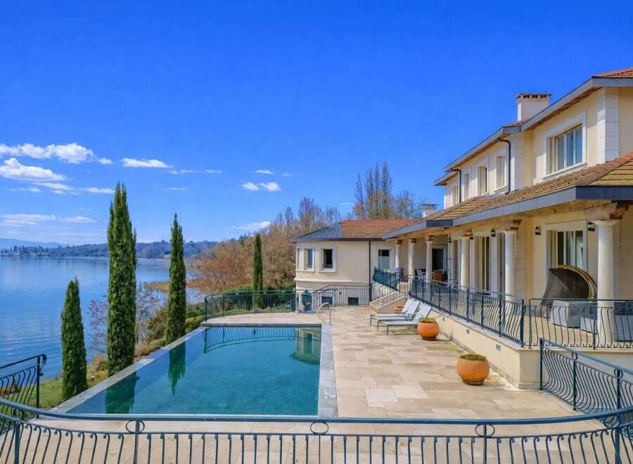 Experience luxurious lakeside living in this stunning property, featuring an infinity pool that seamlessly blends with the serene blue waters.