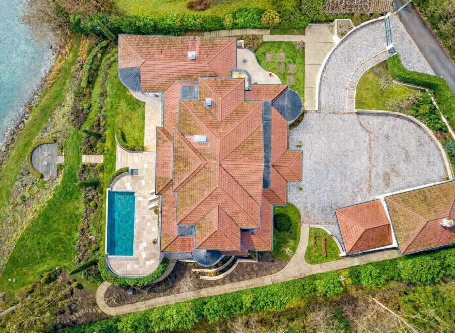 Experience luxury living with this stunning aerial view of a modern mansion featuring a pristine swimming pool and expansive grounds.