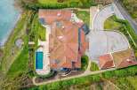 Experience luxury living with this stunning aerial view of a modern mansion featuring a pristine swimming pool and expansive grounds.