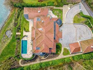 Experience luxury living with this stunning aerial view of a modern mansion featuring a pristine swimming pool and expansive grounds.