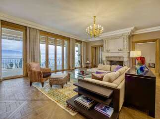 Experience luxurious living in this elegant living room, featuring a grand fireplace and expansive glass doors that open to breathtaking water views.