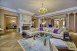 Experience opulent living in this grand living room, featuring a magnificent ornate fireplace and a luxurious sectional sofa adorned with plush accent pillows.