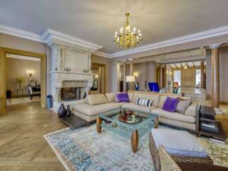 Experience opulent living in this grand living room, featuring a magnificent ornate fireplace and a luxurious sectional sofa adorned with plush accent pillows.