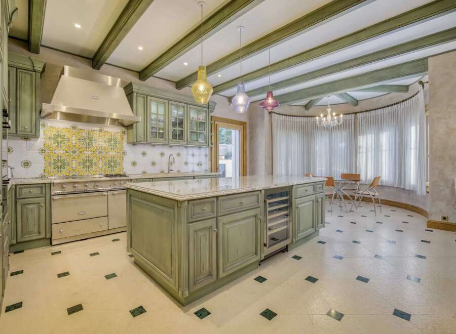 This stunning kitchen boasts custom sage green cabinetry and a large marble-topped island with a built-in wine fridge.
