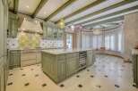 This stunning kitchen boasts custom sage green cabinetry and a large marble-topped island with a built-in wine fridge.
