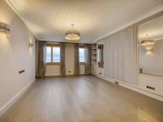 Experience luxury living in this elegantly appointed room featuring a stunning crystal chandelier and sophisticated wall sconces.