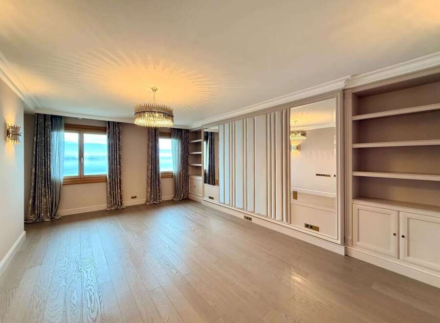 Experience luxury living in this spacious room featuring elegant floor-to-ceiling mirrored wardrobes and built-in shelving.