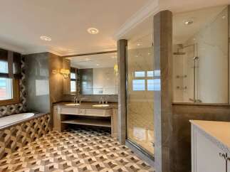 Experience luxury in this stunning bathroom featuring a spacious soaking tub and a separate glass-enclosed shower.