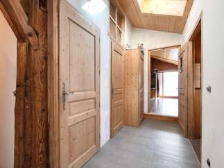 Discover rustic charm in this hallway featuring exposed wooden beams and natural wood doors.