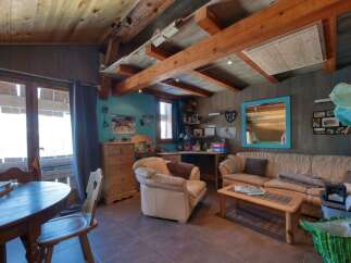 This charming living room features a rustic wooden ceiling with exposed beams, creating a warm and inviting atmosphere.