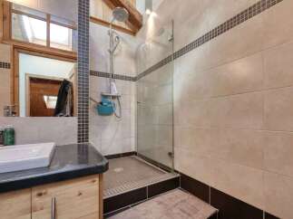 This modern bathroom features a spacious walk-in shower with a glass enclosure and a rainfall showerhead.