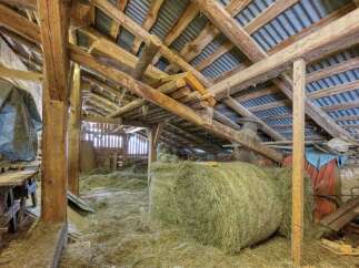 Discover the rustic charm of this barn interior, featuring a substantial hay bale ready for use and a sturdy wooden structure.