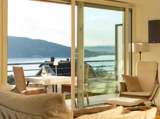 Experience breathtaking waterfront living with this stunning property, featuring expansive glass doors that open to a private balcony overlooking a serene lake and rolling hills.