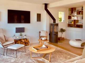 Experience modern living in this beautifully appointed living room, featuring a sleek wood-burning stove and a large flat-screen TV mounted on a clean white wall.