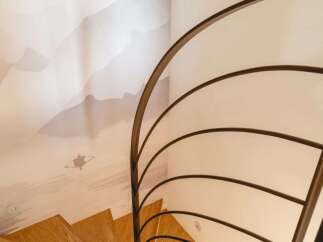 Ascend in style with this stunning spiral staircase, featuring warm wooden treads and a sleek, modern metal railing.