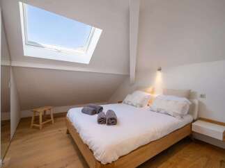 Experience comfort and style in this charming bedroom featuring a cozy bed adorned with plush pillows and neatly folded towels.