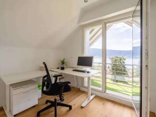 This modern home office features a sleek white desk with a computer setup and an ergonomic black chair, perfect for productive work.