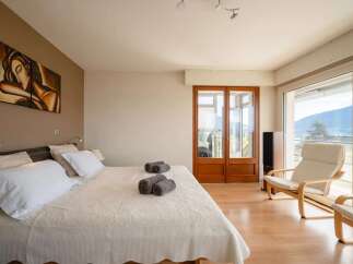 Experience breathtaking mountain views from this luxurious bedroom, featuring a spacious king-size bed adorned with plush white linens and decorative towels.