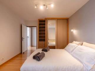 This bedroom features a spacious wardrobe with mirrored doors and a built-in shelving unit, offering ample storage.