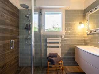 Experience modern luxury in this stunning bathroom featuring a spacious walk-in shower with a rainfall showerhead and elegant wood-look tile accents.