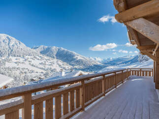 Experience breathtaking mountain views from this charming wooden balcony, perfect for enjoying a serene winter wonderland.