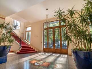 Step into an elegant foyer featuring a grand red carpeted staircase and a stunning crystal chandelier.