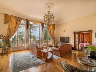 Experience luxurious living in this elegant living room, featuring plush leather seating and a stunning chandelier.