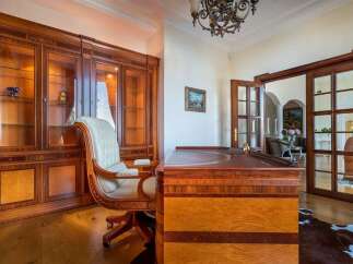 Step into this luxurious home office, featuring a grand executive desk crafted from rich, polished wood with intricate detailing.