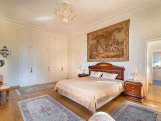 Experience luxurious living in this elegant bedroom, featuring a grand tapestry above a classic wooden bed.