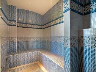 Experience ultimate relaxation in this luxurious steam room, featuring intricate blue and white mosaic tilework throughout.