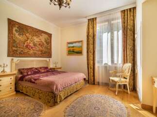 Experience elegant living in this beautifully appointed bedroom, featuring a luxurious tapestry above the bed and rich, ornate curtains framing the window.