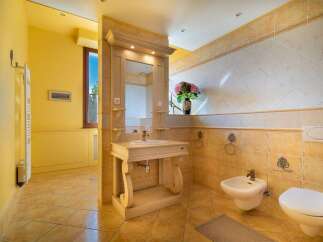 This elegant bathroom features a charming vanity with a sink and mirror, complemented by a bidet and toilet.