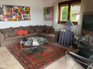 This inviting living room features a spacious sectional sofa adorned with decorative pillows, complemented by a striking abstract artwork above.