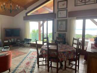 Experience breathtaking lake views from this stunning living and dining area, featuring a vaulted wood-beamed ceiling and expansive windows.