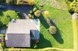 Discover this stunning aerial view of a modern home nestled within a lush, green landscape.