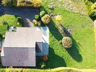 Discover this stunning aerial view of a modern home nestled within a lush, green landscape.