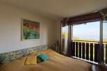Experience breathtaking ocean views from this charming bedroom, featuring a comfortable bed with a floral headboard and direct access to a private balcony.