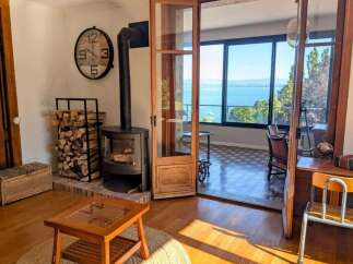 Experience breathtaking lake views from this charming living space, featuring a cozy wood-burning stove and ample natural light.