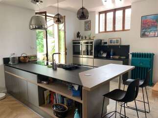 Discover this modern kitchen featuring sleek, dark countertops and integrated appliances, perfect for a culinary enthusiast.
