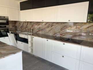 Experience luxury in this modern kitchen featuring sleek white cabinetry and a stunning marble backsplash.