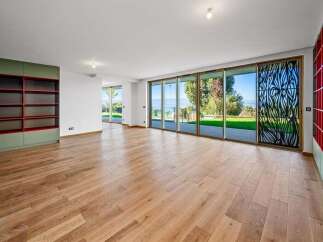 Experience modern living in this spacious room featuring a wall-to-wall sliding glass door system that opens to a scenic outdoor view.