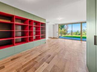 This spacious room features a striking built-in bookshelf with vibrant red shelving, complemented by a calming sage green exterior.
