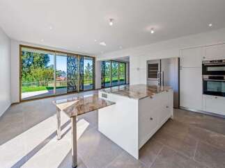 Experience modern luxury in this stunning kitchen featuring a sleek white island with a marble countertop and a pull-out extension.